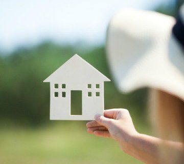 دست یک خانم در حال نگه داشتن یک ماکت خانه به نشانه اجاره دادن ملک