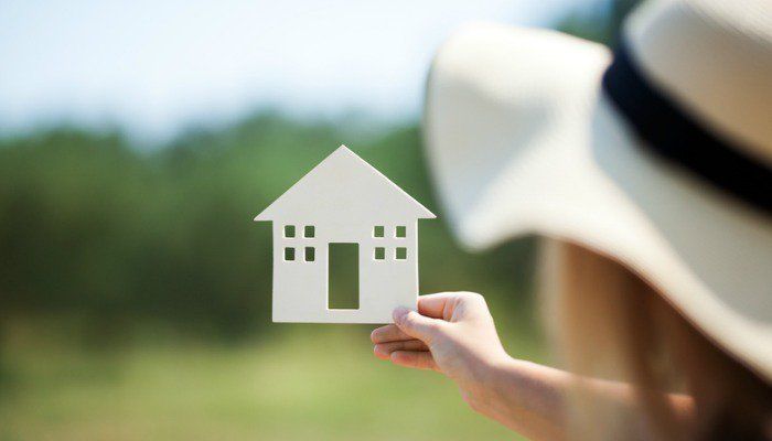 نگه داشتن ماکت خانه توسط یک مرد کلاه دار