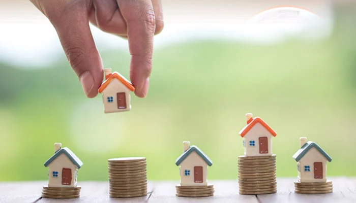 گذاشتن یک ماکت خانه کوچک روی سکه ها