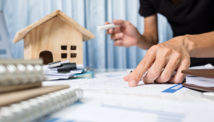 یک عدد ماکت خانی چوبی در کنار یک مرد در حال کشیدن نقشه