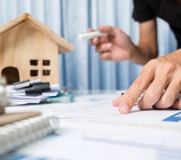 یک پسر در حال نوشتن سند قرار داد در کنار ماکت خانه