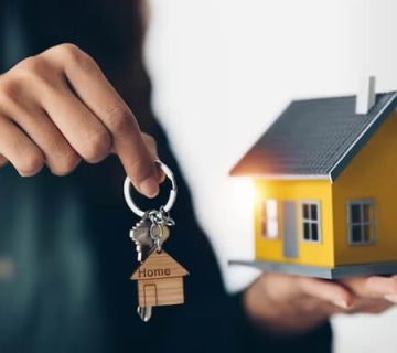 یک پسر که در یکی از دستان خود کلید دارد و در دست دیگر خود یک ماکت منزل