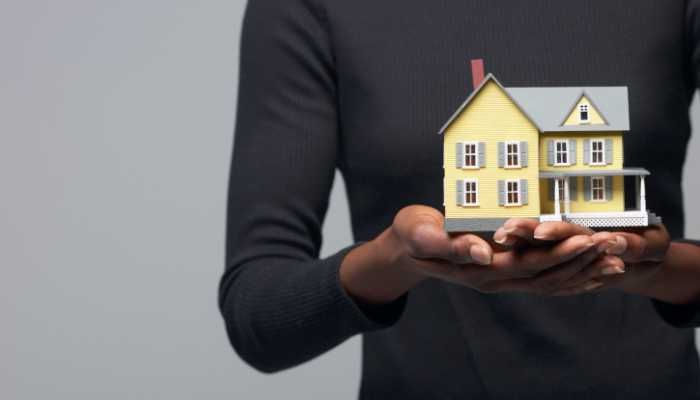 یک شخص که در دست خود ماکت چوبی خانه را دارد.